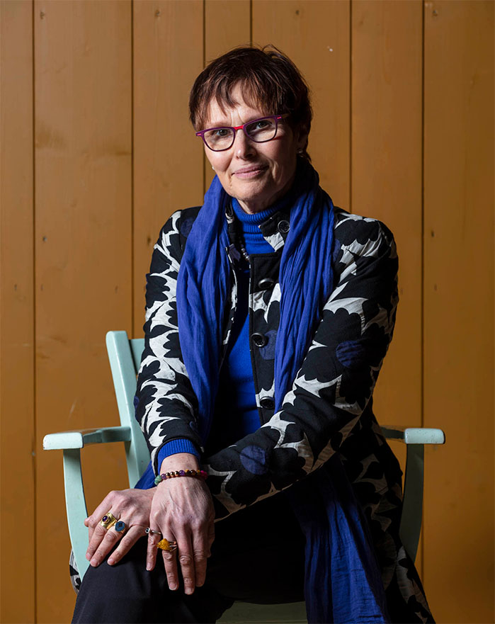 Saskia zittend op een houten stoel, midlife coaching en begeleiding